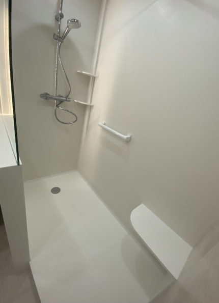Receveur de douche sur mesure en Krion Snow White avec parois murales assorties et bord anti-goutte, réalisé par CM Distribution.