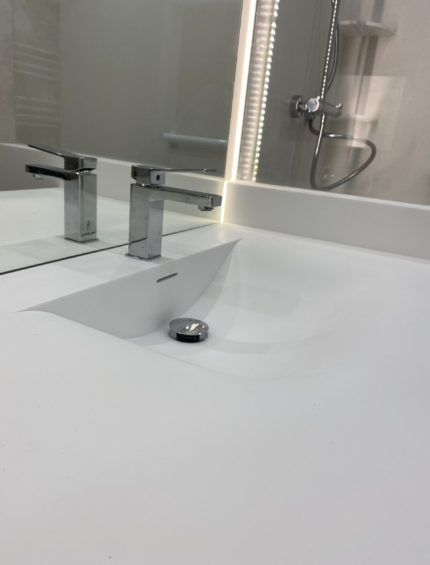 Miroir arrondi rétroéclairé à LED, intégré dans un ensemble salle de bains sur mesure signé CM Distribution.